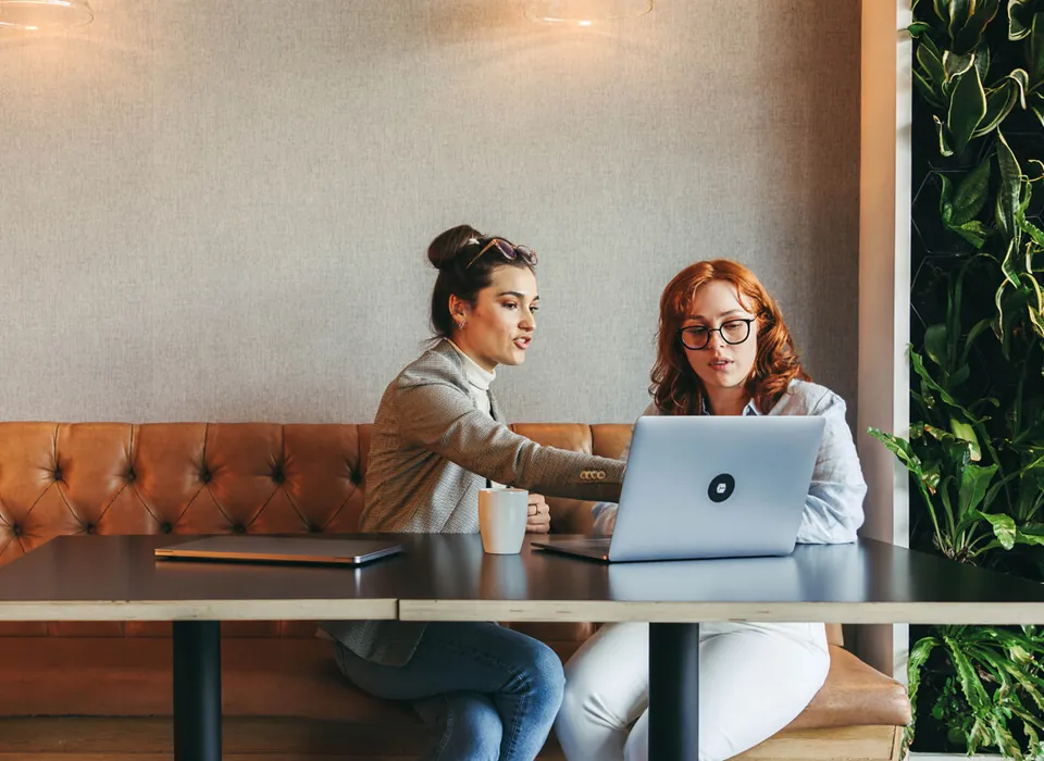 Twee vrouwen werken samen aan een laptop